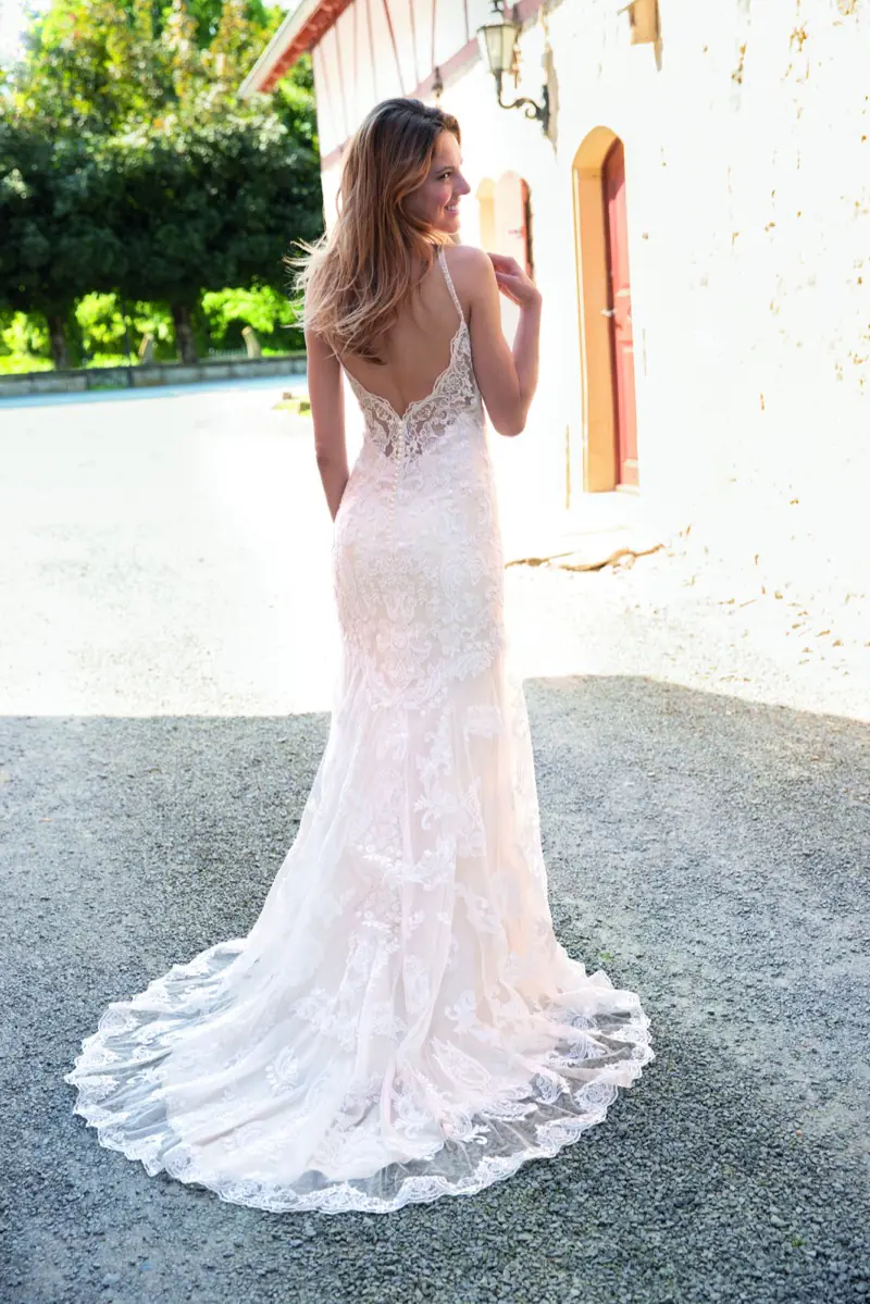 Braut von hinten in einem Spitzenkleid mit langer Schleppe